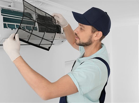 A technician servicing an indoor air conditioning unit